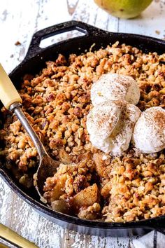 a skillet filled with apple crisp and topped with two scoops of ice cream