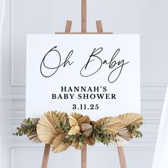 a sign that says oh baby hangs on a easel in front of a white wall