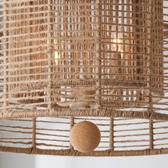 a light fixture made out of woven material with a wooden ball hanging from the side