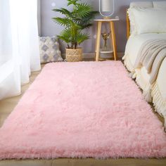 a pink area rug in a bedroom next to a bed with pillows and blankets on it