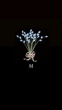 a bouquet of blue flowers sitting on top of a black background with the letter m