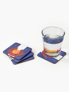 three coasters with different designs on them and one has a glass in the middle