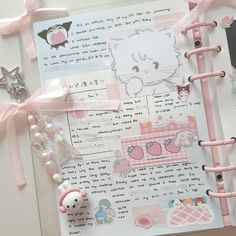 an open hello kitty notebook with pink ribbon and charms on it, next to other items