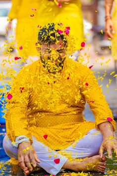 a man sitting on the ground covered in yellow confetti