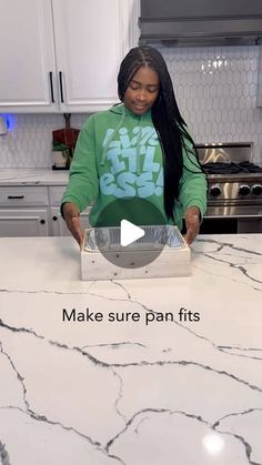 a woman standing in front of a counter with a pizza box on top of it