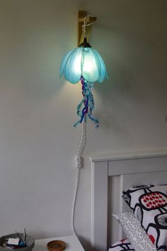 a lamp that is on the side of a wall next to a bed with pillows