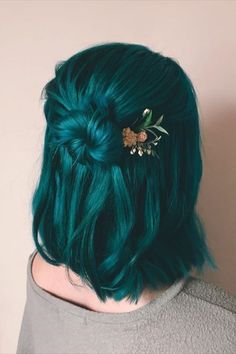 a woman with green hair and a flower in her hair is seen from the back