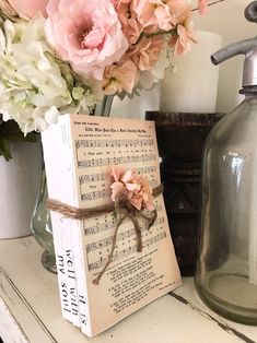 a wooden block with sheet music on it next to flowers and a soap dispenser