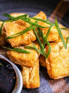 some fried food is on a plate with dipping sauce and green garnishes