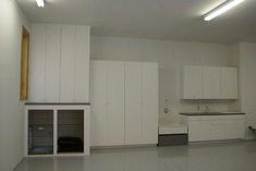 an empty room with white cupboards, cabinets and a dog kennel in it