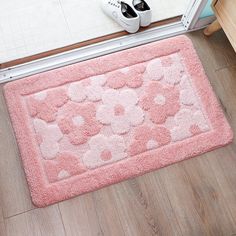 a pink rug on the floor next to a pair of shoes and a door mat