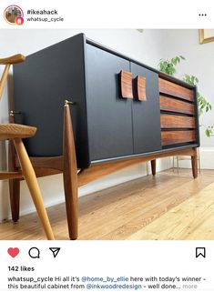 a black and brown cabinet with wooden handles on the bottom, next to a chair