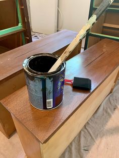 a paint can sitting on top of a wooden table with a brush in the middle