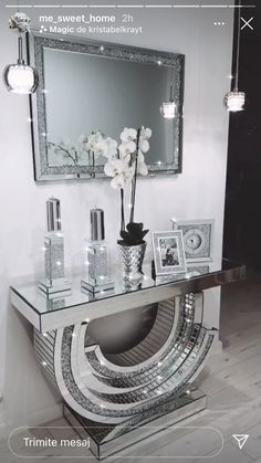 a mirrored console table with white flowers and pictures on the shelf in front of it