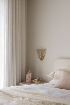 a white bed sitting next to a window in a room with curtains on the windowsill