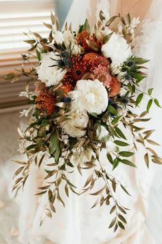 a bridal holding a bouquet of flowers and greenery