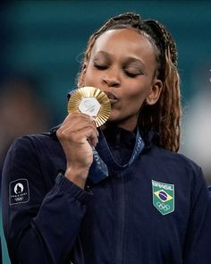 a woman holding a gold medal in her right hand