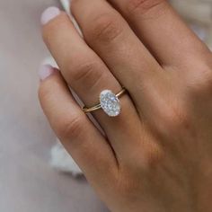 a woman's hand with a diamond ring on top of her finger and the other hand holding an engagement ring