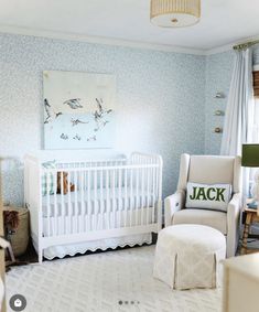 a baby's room with a white crib, rocking chair and blue wallpaper