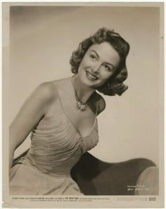 an old black and white photo of a woman in a dress with a smile on her face