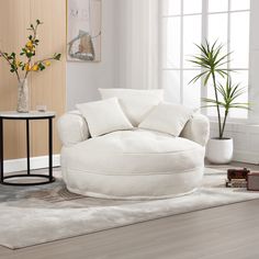 a living room with white furniture and flowers in vases on the side table next to it