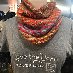 a woman wearing a gray t - shirt with a knitted scarf around her neck