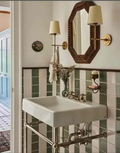 a white sink sitting under a bathroom mirror next to a wall mounted faucet