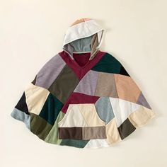 a multicolored hoodie is hanging on a white wall and it's attached to a wooden hanger