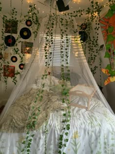 an unmade bed is covered with plants and string lights hanging from the ceiling above it