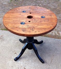 a wooden table sitting on top of a cement floor next to a tree trunk with holes in it