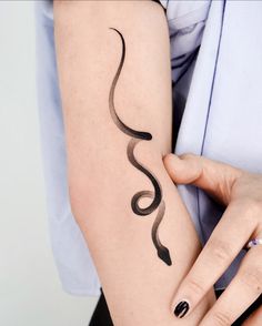 a woman is holding her arm with a snake tattoo on it's left arm