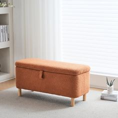 an orange ottoman sitting on top of a carpeted floor next to a book shelf