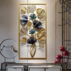 a metal wall sculpture with flowers on it in a living room next to some drawers