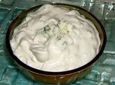 a bowl filled with white sauce sitting on top of a blue cloth covered tablecloth