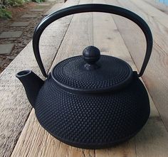 a black tea pot sitting on top of a wooden table