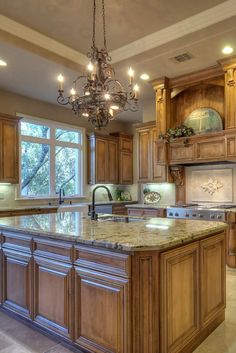 a large kitchen with marble counter tops and wooden cabinets, chandelier hanging from the ceiling