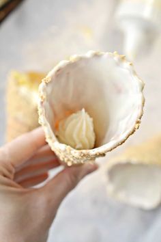 a person holding a pastry in their hand with icing on the inside of it