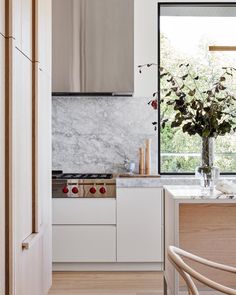 a kitchen with white cabinets and marble counter tops, along with a wooden dining chair