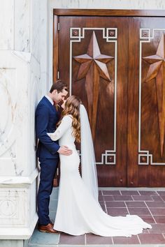 a bride and groom kissing in front of a church door