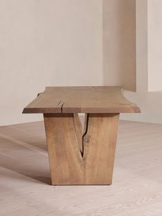 a wooden bench sitting on top of a hard wood floor next to a white wall