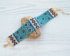 a blue beaded bracelet sitting on top of a wooden table next to a rock