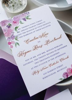 the wedding stationery is set on top of purple and white paper with gold lettering