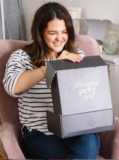 a woman sitting in a chair holding a box