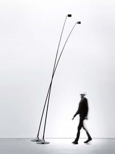 a man walking past two tall black and white lamps