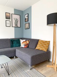 a living room with blue walls and pictures on the wall above the sectional couch,