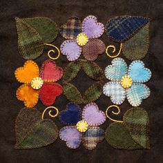 several different colored flowers on a black cloth with gold metal pins in the shape of hearts