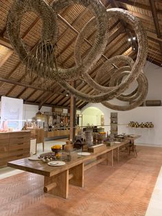 a wooden table topped with plates and bowls under a ceiling covered in bamboo rafters