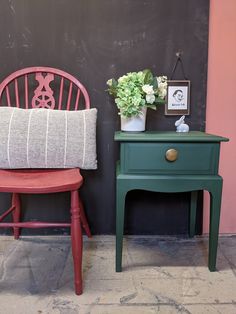 a red chair next to a green table with a potted plant on it