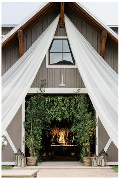 an outdoor wedding venue with white drapes and greenery on the front entrance door