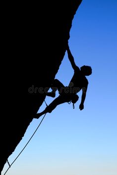 a man climbing up the side of a mountain with his hands in the air royalty images